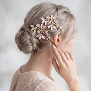 Detail view of rose gold leaf hair pins with rhinestones on a braided bridal updo.