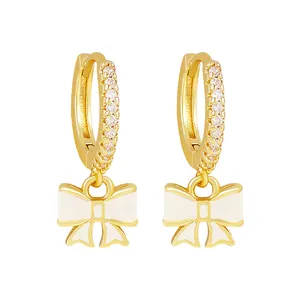 Detailed view of gold-plated hoop earrings with elegant white enamel bow charms