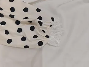 Close-up detail of polka dot puff sleeve with delicate white lace cuff trimming.