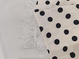 Detail view of vintage white dress with black polka dots and delicate white lace trim