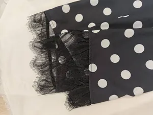 Close-up of black polka dot dress puff sleeves with elegant black lace trim detail.