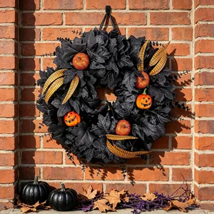 Halloween wreath decoration with black maple leaves and orange pumpkins on brick wall