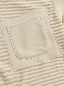 Primo piano di una felpa in velluto a coste beige con dettaglio tasca a toppa