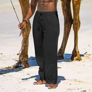 Men's loose black cotton linen trousers shown in a casual beach vacation setting