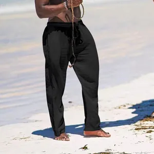 Men's breathable black cotton linen wide-leg trousers shown in a relaxed beach setting.