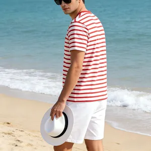 Man wearing a red and white striped t-shirt and white shorts on a sunny beach