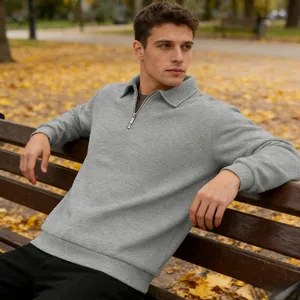 Detailed texture of men's grey jacquard quarter-zip polo sweatshirt in autumn park