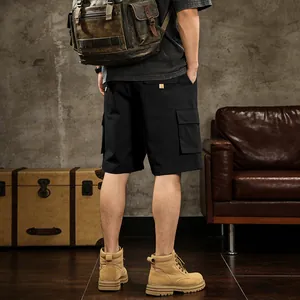 Back view of men's black multi-pocket cargo shorts styled with a vintage backpack.