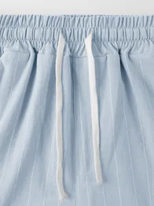 Gros plan d'un pantalon rayé en lin pour homme avec taille élastique et cordon de serrage blanc.
