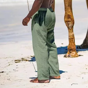 Detailed side view of breathable sage green men's linen pants on a sunny sandy beach
