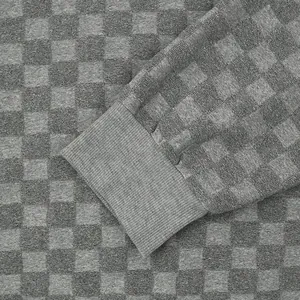 Macro detail showing the textured checkerboard jacquard knit and ribbed cuff of men's sweater