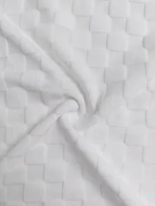Macro view of heavyweight white jacquard knitted fabric with a 3D checkerboard pattern