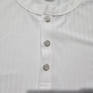 Macro detail of white ribbed Henley t-shirt neckline showing silver-rimmed buttons