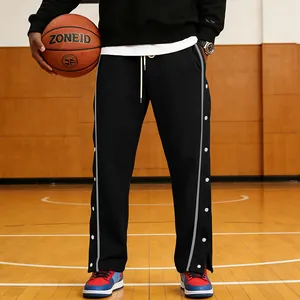 Dettaglio dei pantaloni sportivi neri da uomo con bottoni laterali su campo da basket