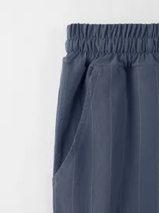 Détail de la taille élastique et de la poche sur un pantalon en lin bleu à rayures