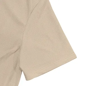 Close-up detail of waffle knit fabric on a men's polo shirt short sleeve cuff in beige
