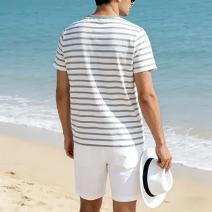Back view of men's casual grey and white striped T-shirt on a beach background
