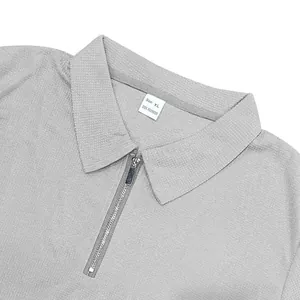 Close-up detail of a grey waffle knit polo shirt with zipper collar and size tag