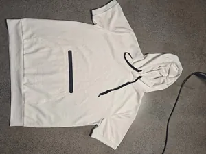 Detail of cream waffle knit mens hooded t-shirt with black drawstring and chest accent.