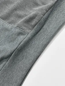 Dettaglio macro del patchwork in velluto a coste grigio e jersey sulla felpa uomo