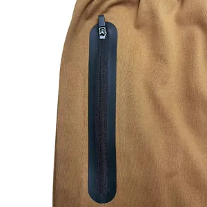 Close-up detail of black waterproof laminated zipper on brown men's casual fitness pants