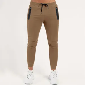 Close-up of men's brown slim-fit sports joggers with black zipper pockets