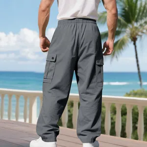 Back view of men's grey cargo pants with large side pockets in a coastal beach setting