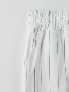 Gros plan d'un pantalon en lin rayé blanc avec taille élastique et détails de poche