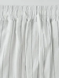 Gros plan d'un pantalon en lin blanc à fines rayures avec taille élastique à cordon serrage