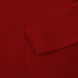 Gros plan détaillé d'un poignet de sweat-shirt rouge montrant la texture du tissu fin.