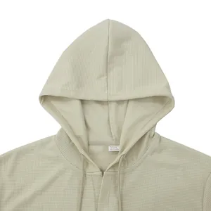 Primo piano dello scollo e della trama a nido d'ape di una t-shirt beige con cappuccio