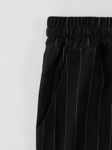 Gros plan d'un pantalon noir à rayures avec taille élastique et détail de poche