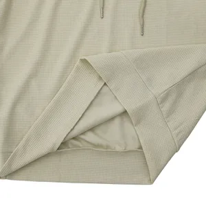 Dettaglio ravvicinato del tessuto waffle beige e dell'orlo di una t-shirt casual con cappuccio