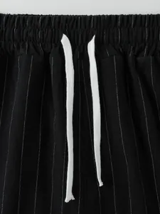 Détail d'un pantalon d'été noir à fines rayures avec taille élastique et cordons blancs