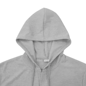 Dettaglio dell'etichetta di una t-shirt grigia con cappuccio da uomo, tessuto sportivo.
