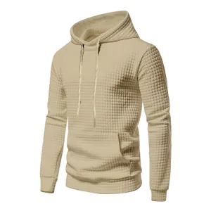 Macro view of the khaki waffle-textured fabric and kangaroo pocket on the men's hoodie.
