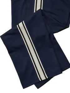 Detailed close-up view of navy blue sports pants with white and black side stripes