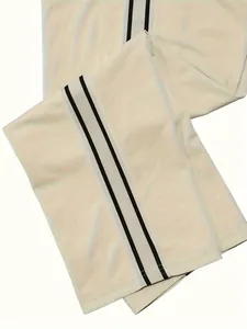 Close-up detail of men's cream sports pants featuring black and white side stripe designs