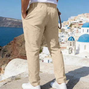 Vue arrière détaillée d'un pantalon décontracté en lin kaki pour homme dans un décor côtier