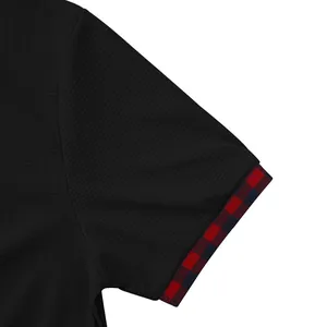 Dettaglio della manica di una t-shirt nera in maglia nido d'ape con polsino a quadri rossi uomo