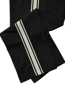 Detailed view of black men's sports pants featuring three white stripes along the side