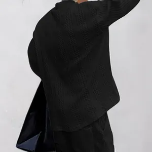 Détail d'un pull en maille jacquard noir pour homme montrant la texture et la coupe large.
