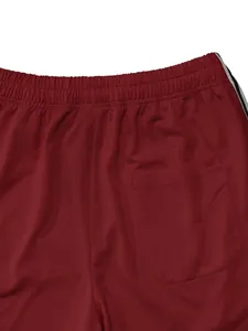 Close-up detail shot of red athletic pants featuring elastic waist and back pocket design