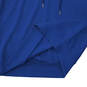 Vista dettagliata della trama a nido d'ape blu e dell'orlo di una t-shirt sportiva con cappuccio.