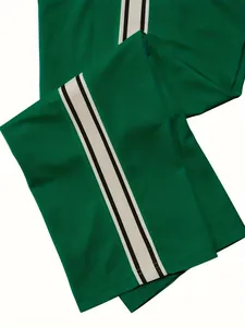 Close-up detail of green men's sports trousers with black and white side stripes
