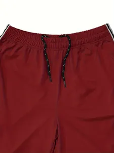 Close-up detail of red athletic pants with elastic drawstring waist and side stripes.