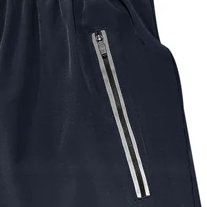 Close-up of men's navy blue athletic shorts featuring a reflective zipper pocket detail.
