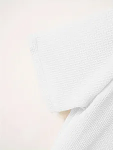 Detailed close-up of heavy waffle knit texture on a men's white polo shirt sleeve.