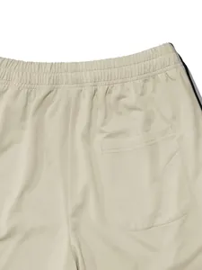 Detailed close-up of men's beige athletic pants with back pocket and elastic waistband