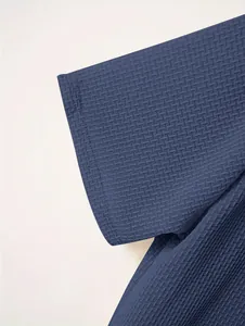 Close-up detail of navy blue waffle texture fabric and stitching on men's polo shirt.